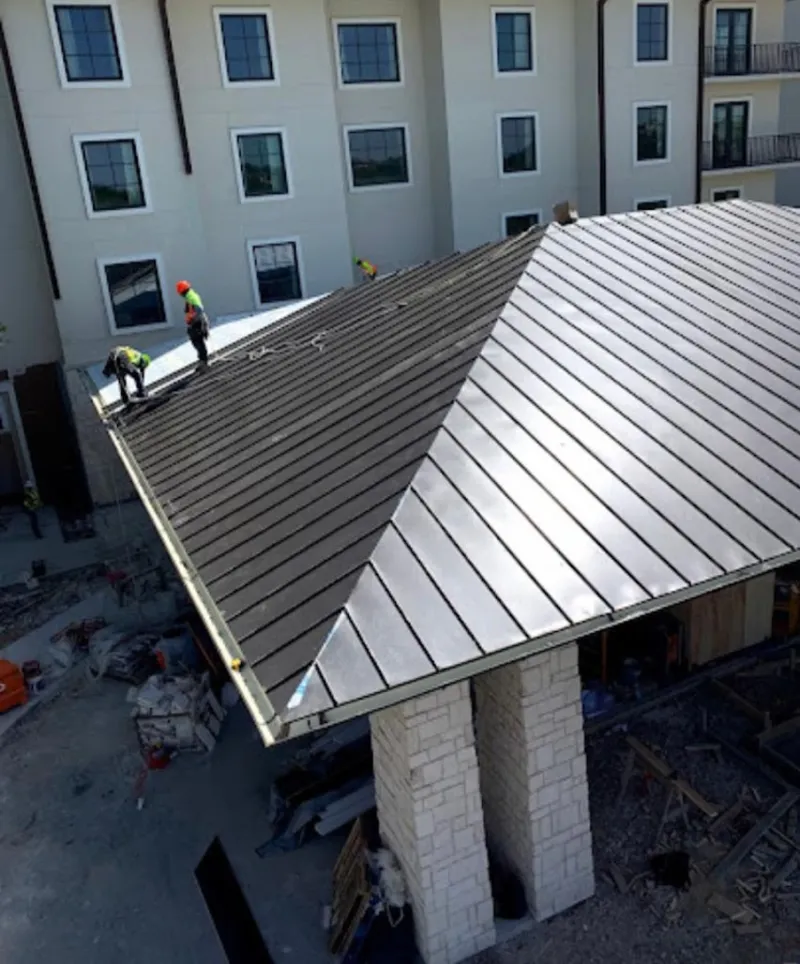 Crew installing standing seam metal roof panels on a commercial project in McCandless